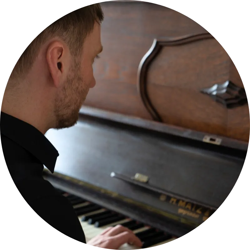 Fabian Günther spielt Klavier und blickt währenddessen in die Kamera Piano Künstler aus Leipzig